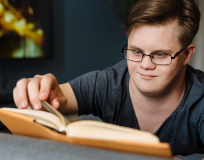 A young man with disability reads accessible information in a book.